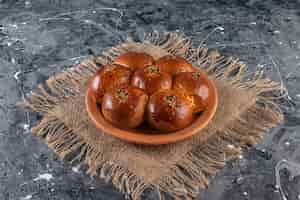 Free photo clay plate of fresh pastry with sesame seeds on marble table.