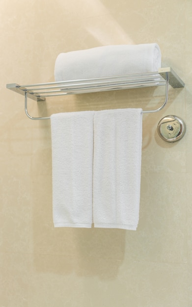Clean white towel on a hanger prepared in bathroom .