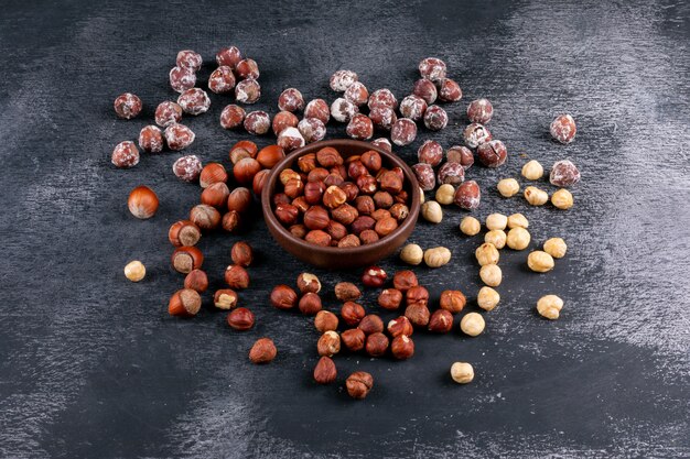 Cleaned and shelled hazelnuts in a brown bowl high angle view on a dark stone table