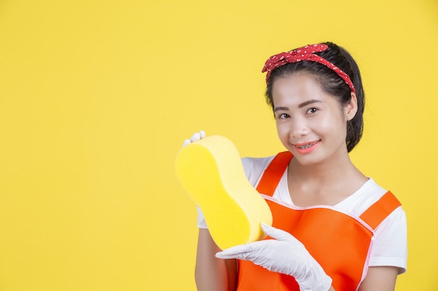 Cleaning . A beautiful woman with a cleaning device on a yellow .