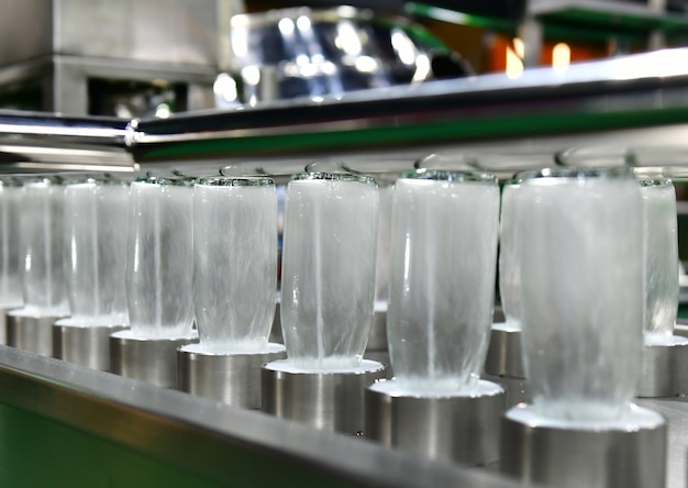 제조시 자동 기계에서 뜨거운 물로 처리중인 음료 제품의 병 유리 병 청소