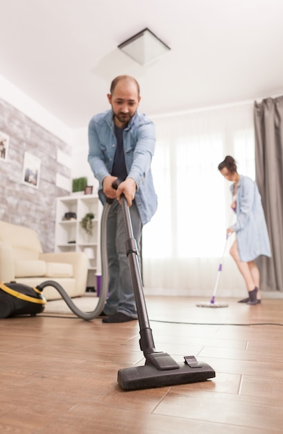 Cleaning floor with vacuum cleaner used by husband