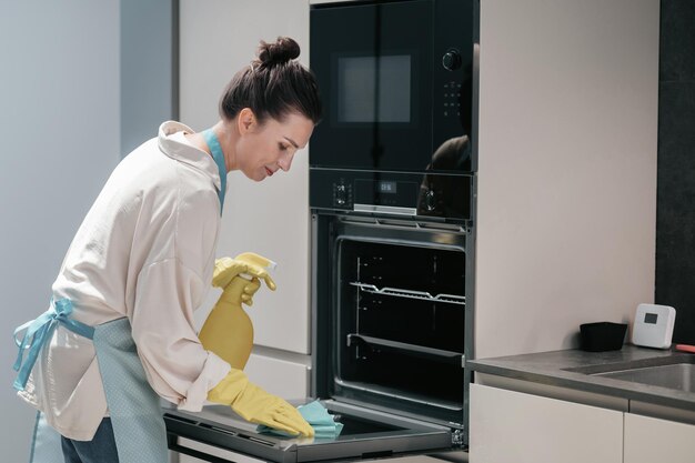 Уборка кухни. Домохозяйка в желтых перчатках убирает кухню