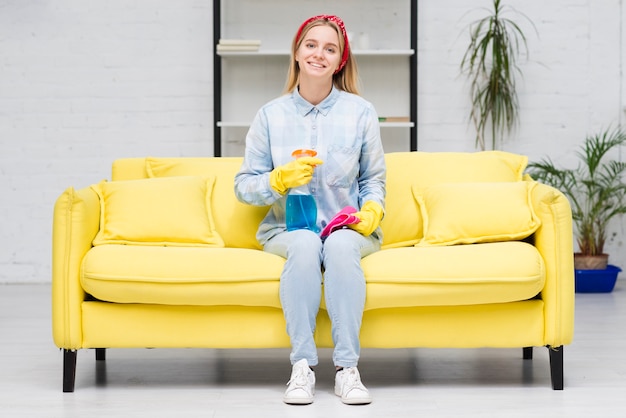 Cleaning woman sitting on couch