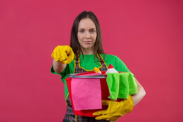  cleaning young woman wearing uniform in gloves holding cleaning tools showing you gesture on isolated pink wall