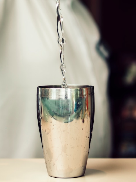 Clear beverage pouring into shaker