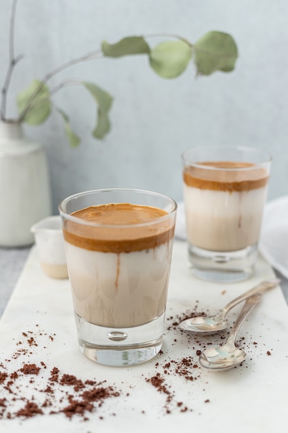 Clear drinking glass with brown liquid on white ceramic saucer