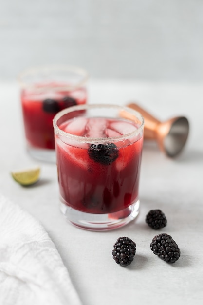 Clear drinking glass with red liquid and ice cubes