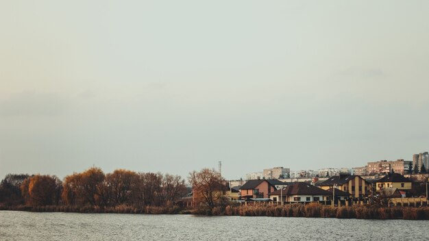 Clear lake surrounded by autumn trees and houses