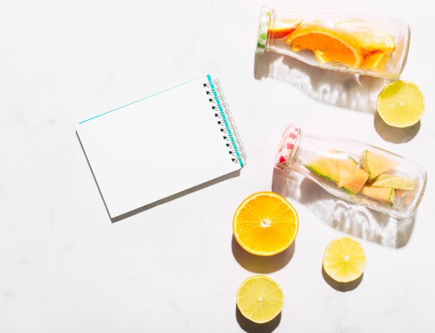 Clear notebook lime orange and glass bottles with cut ​​citrus