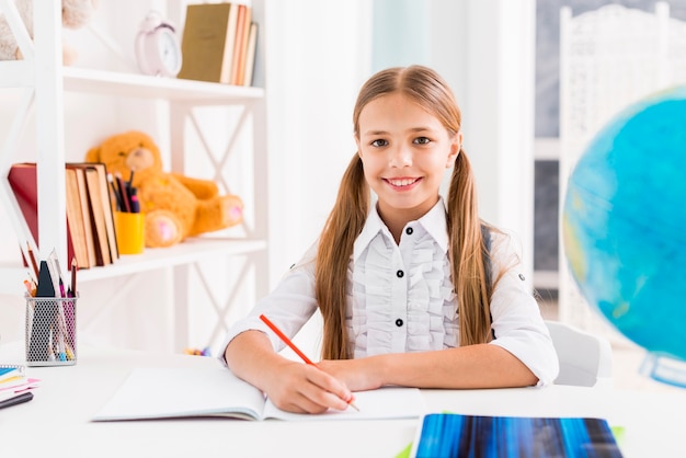 Free photo clever schoolgirl sitting at desk