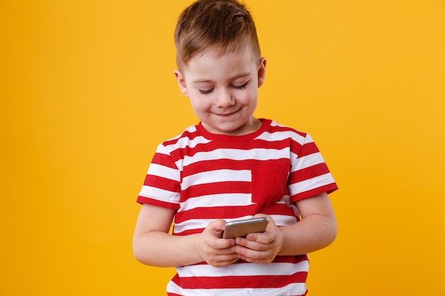 Clever young boy typing message on mobile phone