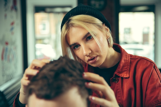 Free photo client during beard shaving in barbershop. female barber at salon. gender equality. woman in the male profession.