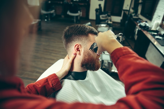 Free photo client during beard shaving in barbershop.