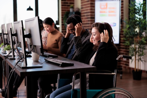 Client helpline operator with chronic health condition using wheelchair in disability friendly office. Woman working at call center customer service helpdesk, living with physical impairment.