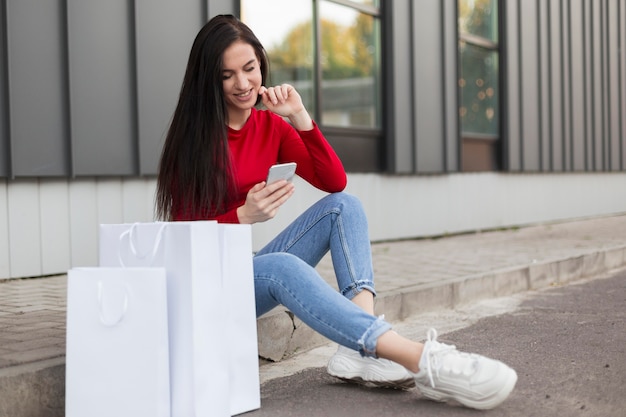 Free photo client in red shirt sitting and using her mobile phone