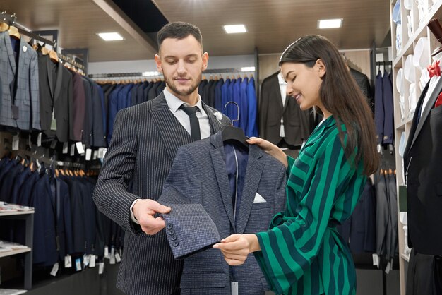 Client and shop consultant looking and trying on jacket.