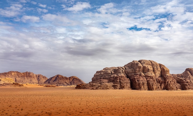 Cliffs and caves on a desert full of dry grass under a cloudy sky during daytime