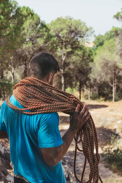 Climber with rope around neck in forest