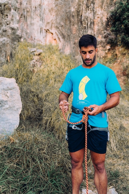 Climber with rope in front of cliffs