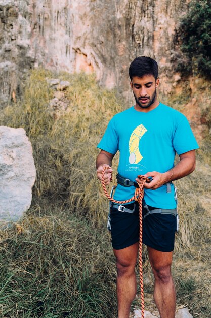 Climber with rope in front of cliffs