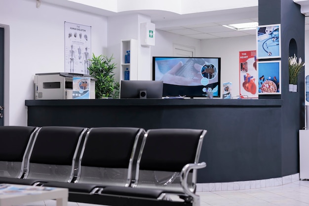 Clinic registration counter in waiting room lobby, computer to make checkup appointments with healthcare report papers. Empty hospital reception desk with medical forms and insurance support.