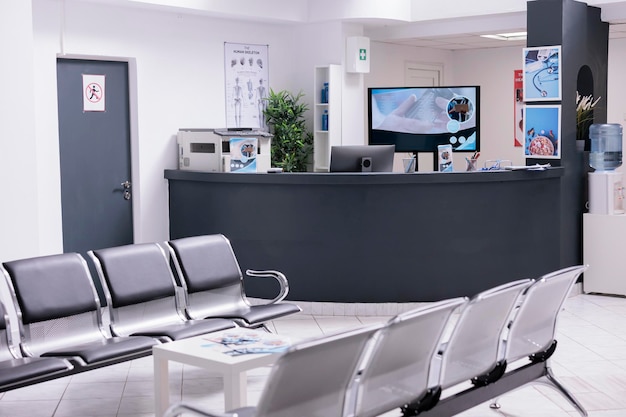 Clinical reception with waiting room in facility lobby, registration counter used for patients with medical appointments. Empty reception desk in health center for checkup visits.