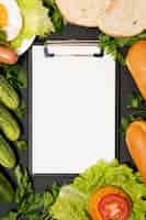 Free photo clipboard mock-up surrounded by vegetables