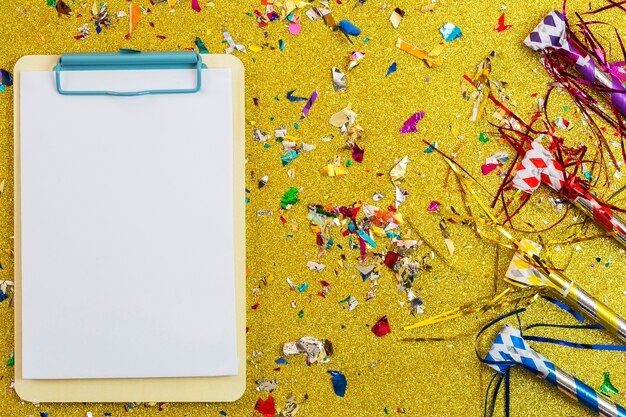 Clipboard near confetti and party horns