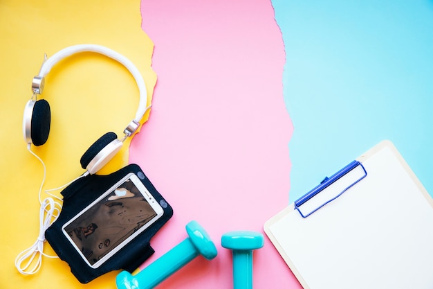 Clipboard near smartphone and dumbbells