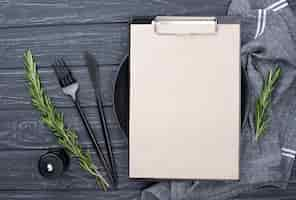 Free photo clipboard on table with plate and cutlery