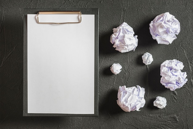 Free photo clipboard and vivid balls of crumpled paper against concrete wall