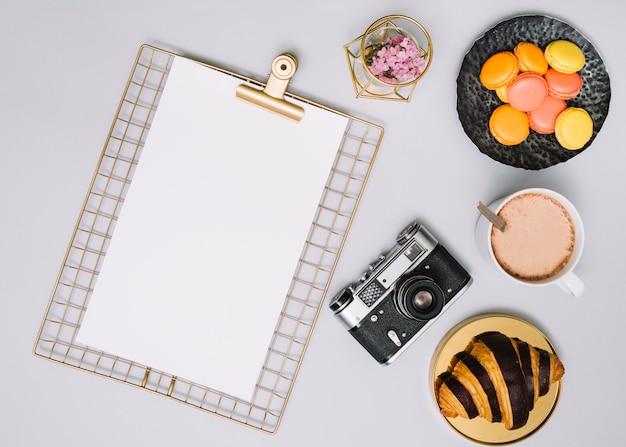 Clipboard with camera, cookies and croissant 