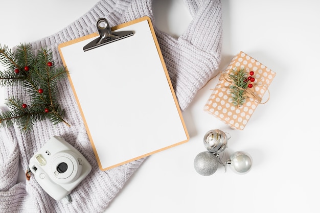 Clipboard with gift box and baubles on table 