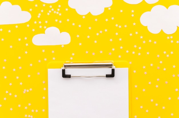 Free photo clipboard with paper clouds on table