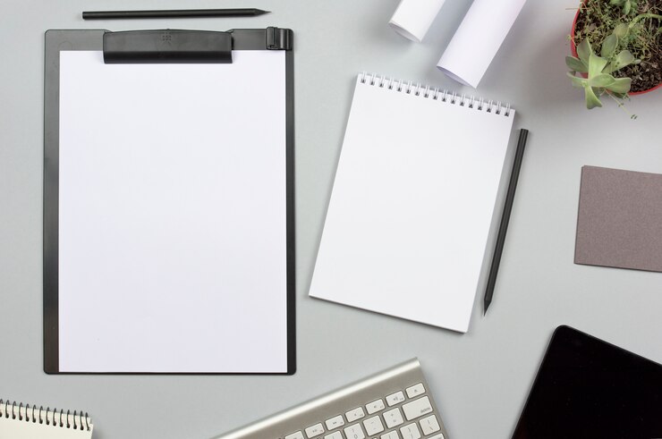 Free Photo clipboard with spiral notepad; pencil and keyboard on gray background
