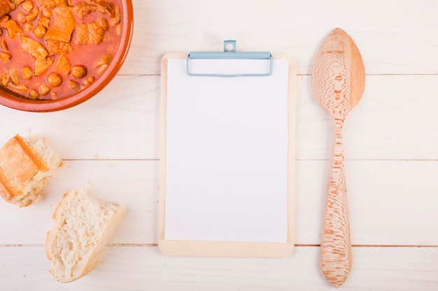 Clipboard with spoon and dish on table