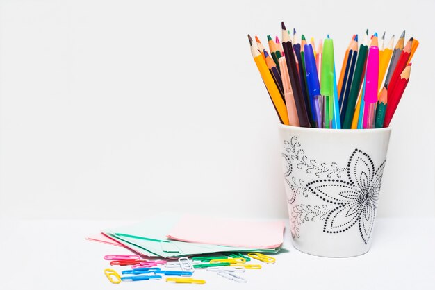 Clips and sticky note near cup with pencils