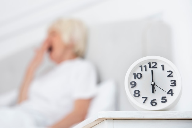 Clock and elder woman on blurred background