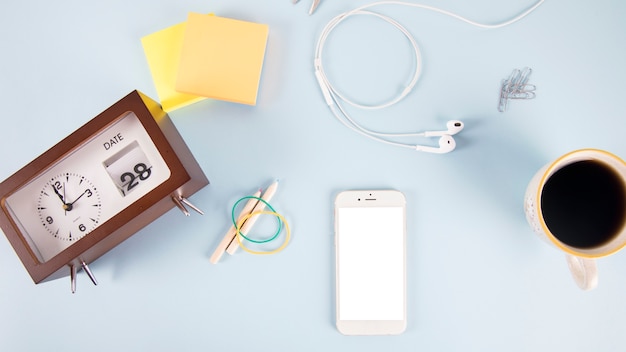 Clock and school supplies near smartphone and drink