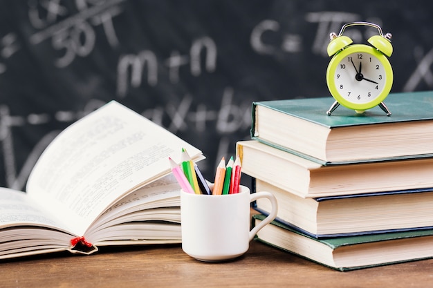 Clock on top of textbooks at teacher desk