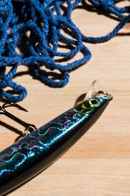 Cloe-up рыболовной приманки с крюком и рыболовной сетью на деревянной поверхности