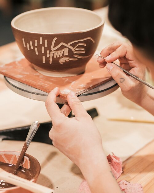 Clos-up of female potter's hand carving on the bowl