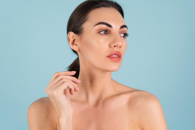 Close beauty portrait of a topless woman with perfect skin and natural make-up, plump nude lips, on a blue background