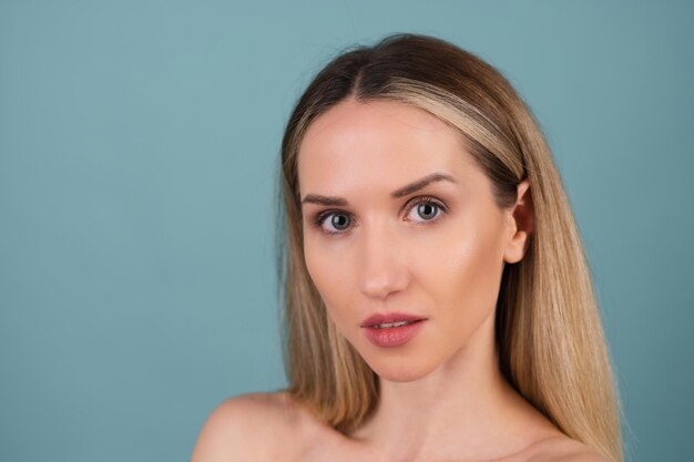 Close beauty portrait of a topless woman with perfect skin and natural make-up, plump nude lips, on a blue background