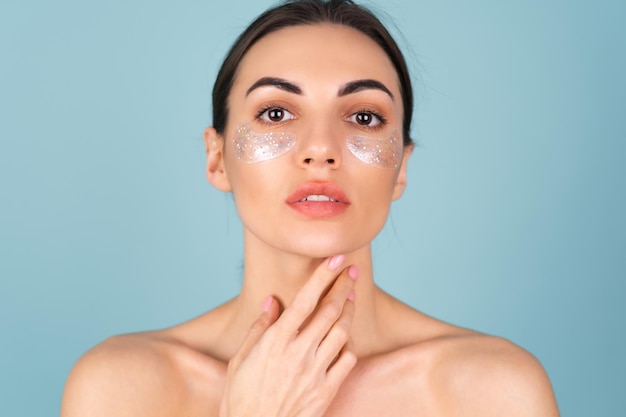 Close beauty portrait of a topless woman with perfect skin and natural make-up, shiny patches under the eyes, to moisturize the skin and relieve puffiness of the face