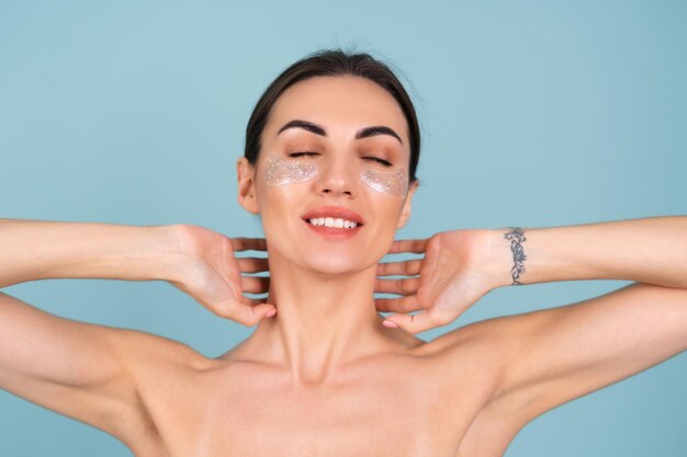 Close beauty portrait of a topless woman with perfect skin and natural make-up, shiny patches under the eyes, to moisturize the skin and relieve puffiness of the face