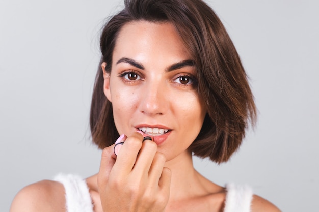 Close beauty portrait of woman with makeup and brown lipstick on gray wall