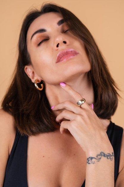 Close fashion portrait of young woman   in black bodysuit with gold cuts, chain, ring posing