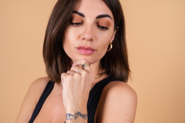 Close fashion portrait of young woman   in black bodysuit with gold cuts, chain, ring posing